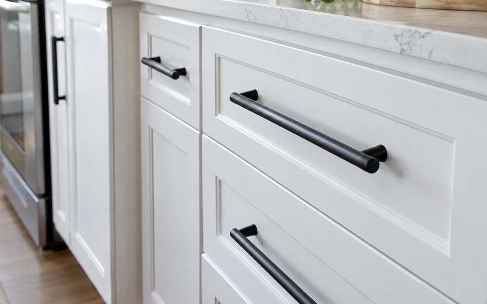 Black bar pulls mounted across white painted cabinet doors.