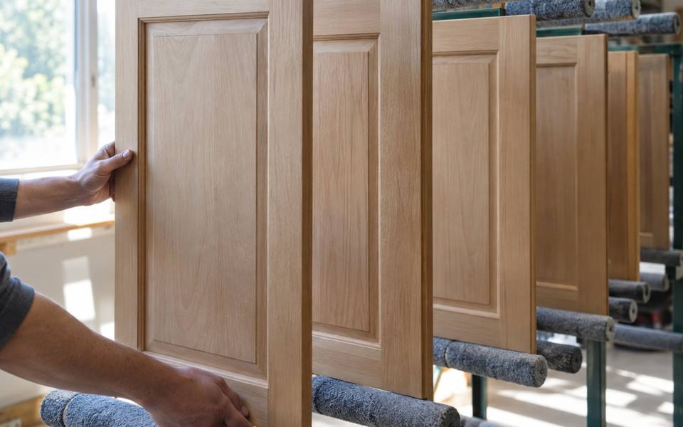 A bare wood cabinet door is cleaned and prepared for its new finish.